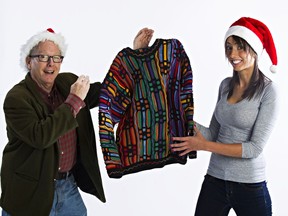 The Edmonton Sun's Graham Hicks, left, passes his Christmas sweater to reporter Claire Theobald in Edmonton, Alta., on Friday, Dec. 12, 2014. When Hicks started Adopt-A-Teen, he wore the sweater every day of the campaign, and is now passing the sweater to Theobald. Hicks started Adopt-A-Teen 15 years ago.