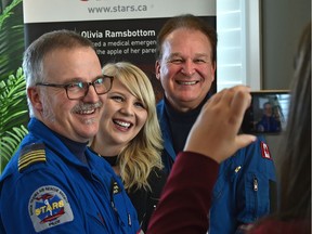 Kaitlyn Julas, a car accident victim who was flown by STARS to the hospital, centre, poses with STARS pilots Grant Wadel, left, and Greg Cars at the 25th edition of the STARS Lottery which took flight Thursday, Jan. 11, 2018.