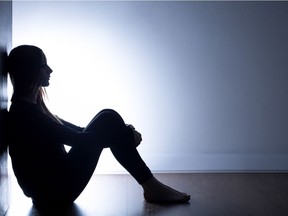 Teenager with depression sitting alone in dark room. Getty Images/iStock Photo