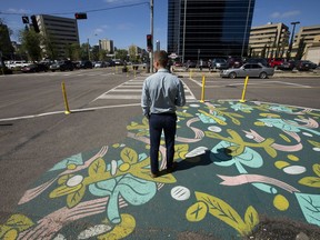 A pedestrian walks across a street painting along Jasper Avenue near 111 Street in Edmonton on Aug. 8, 2017.