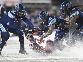 Toronto Argonauts defensive back Jermaine Gabriel, linebacker Marcus Ball and defensive back Qudarius Ford tackle Calgary Stampeders running back Roy Finch during the Grey Cup on Nov. 26, 2017