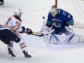 Edmonton Oilers' Connor McDavid, left, puts a shot wide of the net behind Vancouver Canucks goalie Jacob Markstrom, of Sweden, during the third period of an NHL hockey game in Vancouver, B.C., on Saturday, October 7, 2017.
