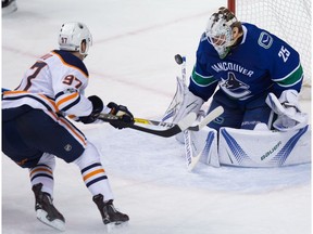 Edmonton Oilers' Connor McDavid, left, puts a shot wide of the net behind Vancouver Canucks goalie Jacob Markstrom, of Sweden, during the third period of an NHL hockey game in Vancouver, B.C., on Saturday, October 7, 2017.