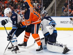 Patrick Maroon #19 of the Edmonton Oilers battles against Dmitry Kulikov #5 and goaltender Connor Hellebuyck #37 of the Winnipeg Jets during National Hockey League action at Rogers Place in Edmonton on Sunday, Dec. 31, 2017.