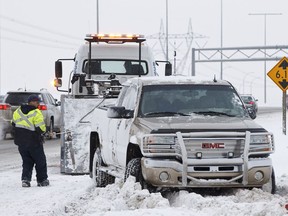 An Alberta Motor Association tow truck driver hooks up a GMC Sierra pickup truck that spun out on the eastbound shoulder of Anthony Henday Drive near the Terwillegar exit in Edmonton, Alta., on Sunday, Dec. 29, 2013.