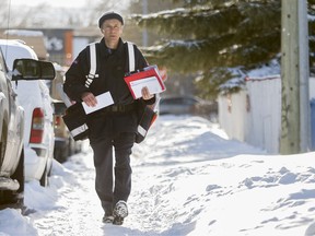 A Canada Post worker delivers mail door-to-door in northwest Calgary, Alta., on Wednesday December 11, 2013.