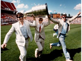 Left to right, Edmonton Oilers Paul Coffey, Wayne Gretzky and Kevin Lowe hold the Stanley Cup aloft as they run across the Commonwealth Stadium grass during a community gathering for the repeat Stanley Cup Champion Oilers at Commonwealth Stadium on June 2, 1985. The Oilers won their second Stanley Cup Championship by beating the Philadelphia Flyers in five games on May 30, 1985 in Edmonton.