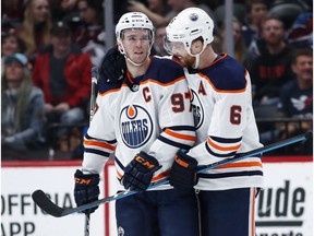 Edmonton Oilers defenseman Adam Larsson, right, congratulates center Connor McDavid on his empty-net tally to notch a hat trick against the Colorado Avalanche in the third period of an NHL hockey game Sunday, Feb. 18, 2018, in Denver, Colorado.