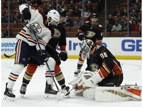 Edmonton Oilers left wing Jujhar Khaira, left, battles for the puck with Anaheim Ducks goaltender John Gibson, right, and defenseman Brandon Montour during the first period of an NHL hockey game in Anaheim, Calif., Friday, Feb. 9, 2018.