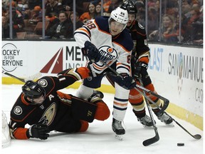 Edmonton Oilers defenceman Brandon Davidson, centre, steps over Anaheim Ducks center Ryan Kesler, left, to control the puck as defenseman Hampus Lindholm, of Sweden, trails during the second period of an NHL hockey game in Anaheim, Calif., Friday, Feb. 9, 2018.