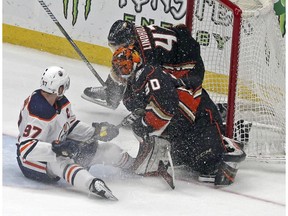 Edmonton Oilers center Connor McDavid tangles with Anaheim Ducks defenseman Hampus Lindholm (47) and goalie Ryan Miller (30), knocking the goal loose in overtime in an NHL hockey game in Anaheim, Calif., Sunday, Feb. 25, 2018. The Oilers won in a shootout, 6-5.