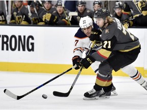 Edmonton Oilers left wing Milan Lucic (27) and Vegas Golden Knights center William Karlsson vie for the puck during the first period of an NHL hockey game Thursday, Feb. 15, 2018, in Las Vegas.
