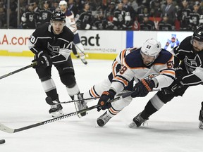 Edmonton Oilers left wing Anton Slepyshev, center, of Russia, and Los Angeles Kings defenseman Drew Doughty, right, reach for the puck as left wing Tanner Pearson skates in during the first period of an NHL hockey game Saturday, Feb. 24, 2018, in Los Angeles.