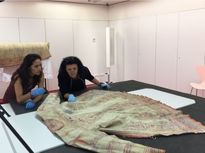 Paz Núñez-Regueiro, heritage curator, left, and Carole Charette examine a Naskapi coat.