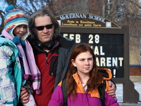Semyon Chaichenets with his daughters, Anna, 10, who is in the extensions program for gifted kids, and Maria, 6, pose in front of McKernan School in Edmonton, Feb. 27, 2018.
