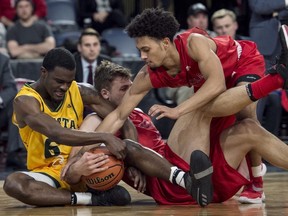 Alberta Golden Bears' Dwan Williams, left, fights for a loose ball with Acadia Axemen Erik Nissen, centre, and Mitchell Tempro during the first half of consolation action in the U Sports men's basketball national championship in Halifax on Saturday, March 10, 2018.