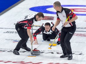 Ontario skip John Epping follows as lead Tim March, left, and second Patrick Janssen sweep as they play Quebec at the Tim Hortons Brier curling championship at the Brandt Centre in Regina on March 4, 2018