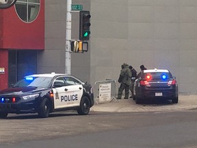 EPS officer getting into full bomb gear at corner of 102 Street and 103 Ave.