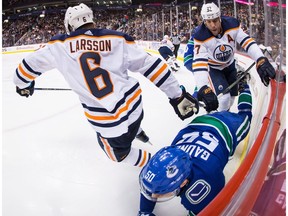 Edmonton Oilers left wing Milan Lucic (27) checks Vancouver Canucks centre Brendan Gaunce (50) behind Edmonton defenceman Adam Larsson (6) in Vancouver on Thursday, March 29, 2018.