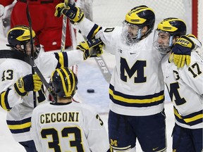 Michigan's Tony Calderone (17) celebrates his goal with teammates Cooper Marody (20), Jake Slaker (13) and Joseph Cecconi (33) during the first period of the NCAA northeast regional championship hockey game against Boston University in Worcester, Mass., Sunday, March 25, 2018.