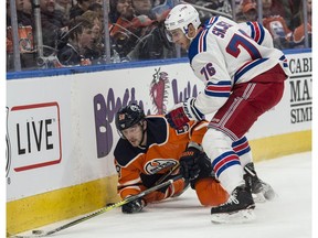Anton Slepyshev of the Edmonton Oilers, is tripped up by Brady Skjei of the New York Rangers at Rogers Place in Edmonton  on March 3, 2018.  Photo by Shaughn Butts / Postmedia