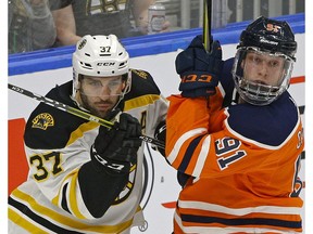 Edmonton Oilers forward Drake Caggiula (right) is checked by Boston Bruins Patrice Bergeron in Edmonton on Feb. 20, 2018. (File)