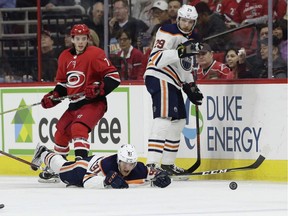 Edmonton Oilers' Drake Caggiula (91) fall to the ice chasing the puck as Carolina Hurricanes' Derek Ryan (7) watches with Oilers' Leon Draisaitl (29), of Germany, during the second period of an NHL hockey game in Raleigh, N.C., Tuesday, March 20, 2018.