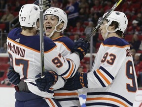 Edmonton Oilers' Matt Benning, center, is congratulated by Connor McDavid, left, and Ryan Nugent-Hopkins (93) following Benning's goal against the Carolina Hurricanes during the first period of an NHL hockey game in Raleigh, N.C., Tuesday, March 20, 2018.