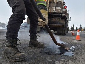 A crew fills in potholes on Kingsway Avenue and 121 Street in Edmonton on March 1, 2018.