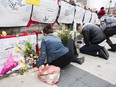 People read and pay tribute at a memorial for the victims along Yonge Street the day after a driver drove a rented van down sidewalks Monday afternoon, striking pedestrians in his path, in Toronto, Tuesday, April 24, 2018. (THE CANADIAN PRESS)