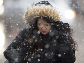 A pedestrian makes her way through the falling snow near Jasper Avenue and 101 Street, in Edmonton on Monday, April 16, 2018.