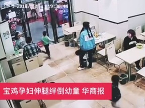 In this screenshot, a pregnant woman in China is captured on CCTV tripping a young boy.