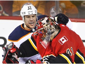 Edmonton Oilers' Milan Lucic (27) fights with Calgary Flames goalie Mike Smith (41) in Calgary on Saturday, March 31, 2018.