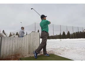 Rob Turner (left) and Barry Shymanski hit the driving range at Victoria Park Golf Course on a snowy spring opening day in Edmonton, on Friday, April 13, 2018. They're Highlands Golf Club members and were out early looking forward to their first round of golf this spring. (Ian Kucerak)