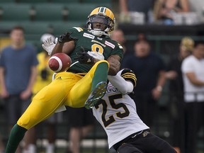 Edmonton Eskimos Kenny Stafford (8) can't hang onto the ball as he is pulled down by Hamilton Tiger-Cats Jumal Rolle (25) during first quarter CFL action on Friday, June 22, 2018 in Edmonton.