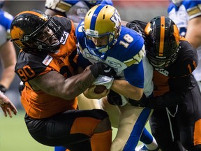Winnipeg Blue Bombers quarterback Alex Ross, centre, is sacked by B.C. Lions' Odell Willis, right, as Davon Coleman helps bring him down during the first half of a pre-season CFL football game in Vancouver, on Friday June 8, 2018.