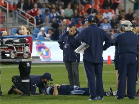 Coaching staff and players gather around Toronto Argonauts quarterback Ricky Ray as he lays injured on the field during the second half of CFL football game action against the Calgary Stampeders at BMO Field in Toronto, Ontario on Saturday June 23, 2018.