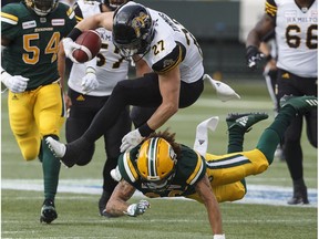 Hamilton Tiger-Cats Mercer Timmis (27) is taken out be Edmonton Eskimos Aaron Grymes (36) during first half CFL action in Edmonton on Friday June 22, 2018.