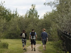Friends take a walk along a path on top of the riverbank overlooking the Fort Edmonton Footbridge in Edmonton, on Wednesday, June 13, 2018.