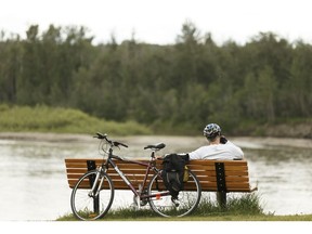 A cyclist rests for a moment while looking over the North Saskatchewan River at the Fort Edmonton Footbridge in Edmonton, on Wednesday, June 13, 2018.