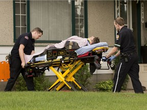 A man is taken to an ambulance after being rescued from a hole that collapsed on top of him near104th Avenue and 42nd Street on Thursday, June 14, 2018 in Edmonton.