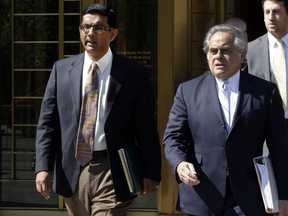 In this May 20, 2014 file photo, conservative scholar and filmmaker Dinesh D'Souza, left, accompanied by his lawyer Benjamin Brafman leaves federal court, in New York. (AP Photo/Richard Drew)