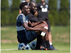 Vancouver Whitecaps midfielder Alphonso Davies, front, sits with staff coach Pa-Modou Kah during MLS soccer team practice in Vancouver on Monday, July 23, 2018.