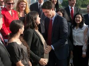 In this Aug. 10, 2015 file photo, then-federal Liberal Leader Justin Trudeau greets pregnant candidate Christine Poirier at an event in Montreal.