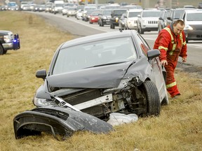 A tow truck driver assesses a crunched car on Deerfoot Trail in Calgary on Oct. 15, 2014. Last December the province issued an order limiting cumulative auto rate hikes to five per cent, effective this November.