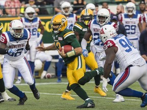 Edmonton Eskimos Mike Reilly (13) runs the ball under pressure from Montreal Alouettes Fabion Foote (94) during first half CFL action in Edmonton, Saturday, Aug. 18, 2018.