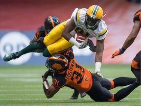 Edmonton Eskimos receiver D'haquille Williams, top, is upended by B.C. Lions' Otha Foster III (31) during CFL action in Vancouver on Aug. 9, 2018.