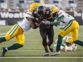 Hamilton Tiger-Cats' Alex Green scores a touchdown against the Edmonton Eskimos' Christophe Mulumba-Tshimanga, left, and Nicholas Taylor, right, during the first half of CFL football action in Hamilton on August 23, 2018.