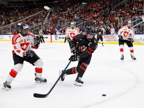Canada's Alexis Lafreniere (11) evades Switzerland's Noah Delemont (6) during first period round-robin Hlinka Gretzky Cup hockey action in Edmonton on August 6, 2018.