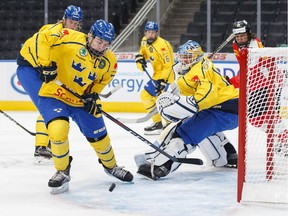 Sweden's Tobias Bjornfot (7) clears the puck away from teammate and goalie Hugo Alnefelt (1) during first period Hlinka Gretzky Cup action against Switzerland, in Edmonton on Aug. 7, 2018.